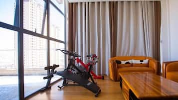 A modern room with a large window, an exercise bike, a wooden table, and a sofa.