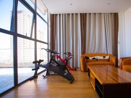 A modern room with a large window, an exercise bike, a wooden table, and a sofa.
