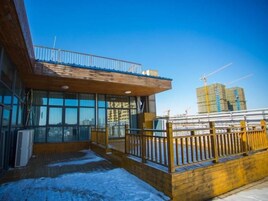 A modern building with large windows, a wooden deck, and a balcony.
