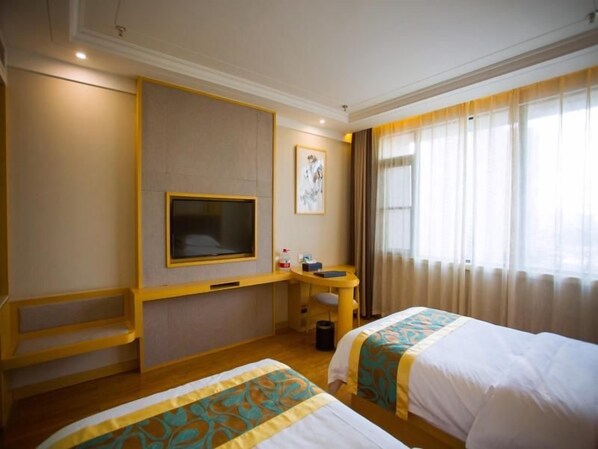 A hotel room with two beds, a television, a desk, and a window with curtains.