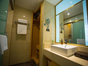 Une salle de bain moderne avec un grand miroir, un lavabo et un espace douche.