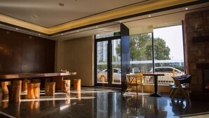 Un vestíbulo moderno con suelo pulido, una recepción y un área de descanso con sillas y mesas.