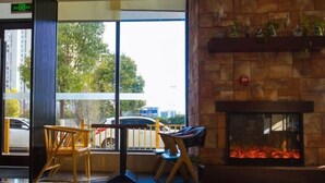 Un interior moderno con chimenea de piedra, ventanas amplias y suelo reflectante.