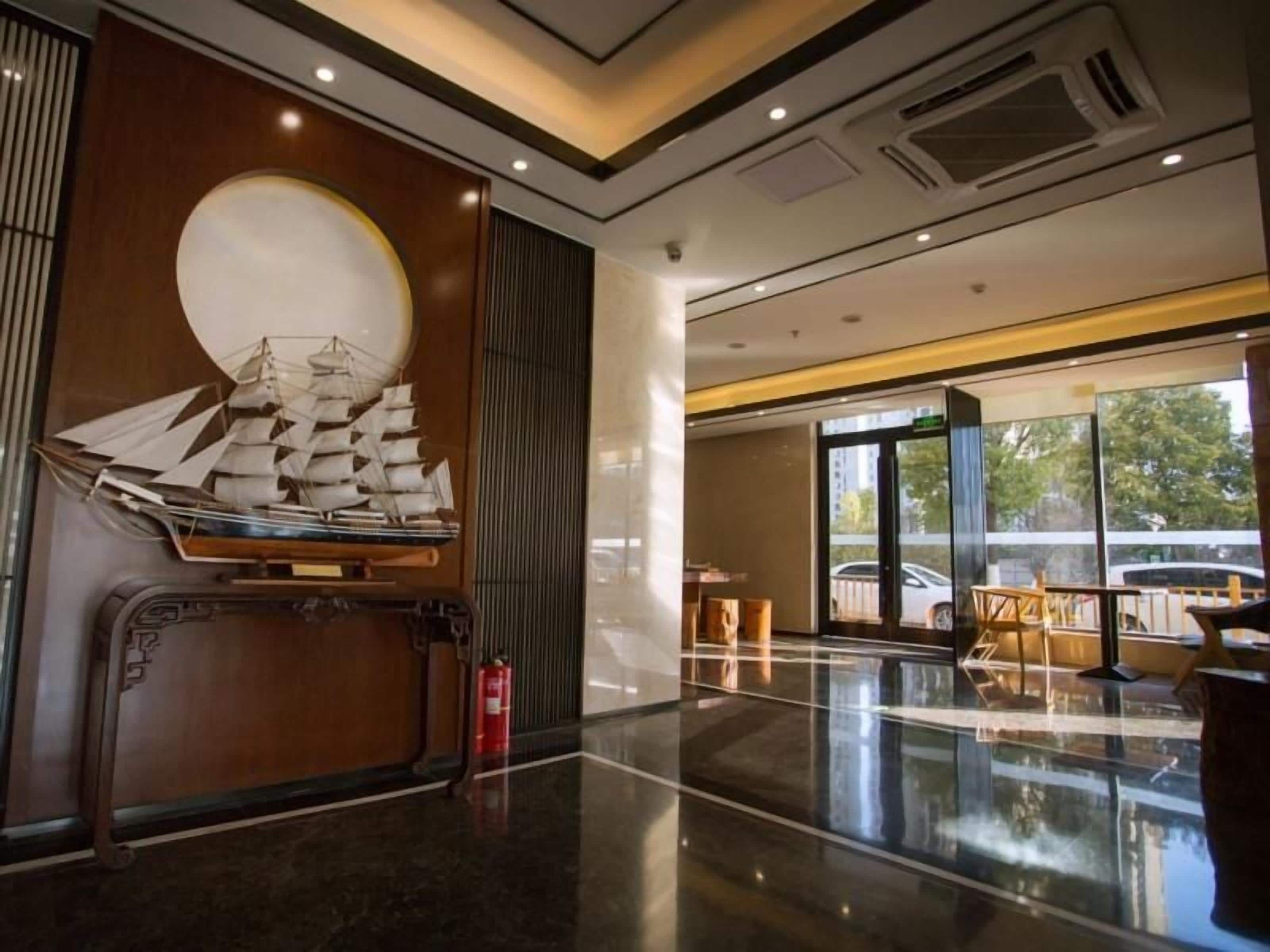 A modern lobby with a large wooden panel, a ship model, and a fire extinguisher.