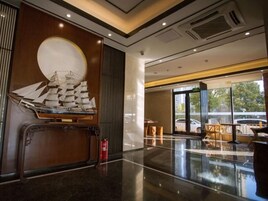A modern lobby with a large wooden panel, a ship model, and a fire extinguisher.