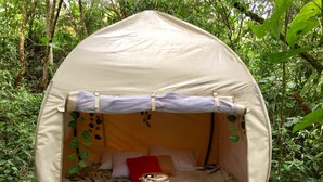 A small, enclosed, tent-like structure with a bed inside, surrounded by dense greenery. - Mot Mot Glamping (Filandia)
