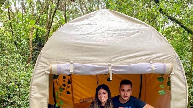 A tent with a person and a child inside, surrounded by greenery. - Mot Mot Glamping (Filandia)
