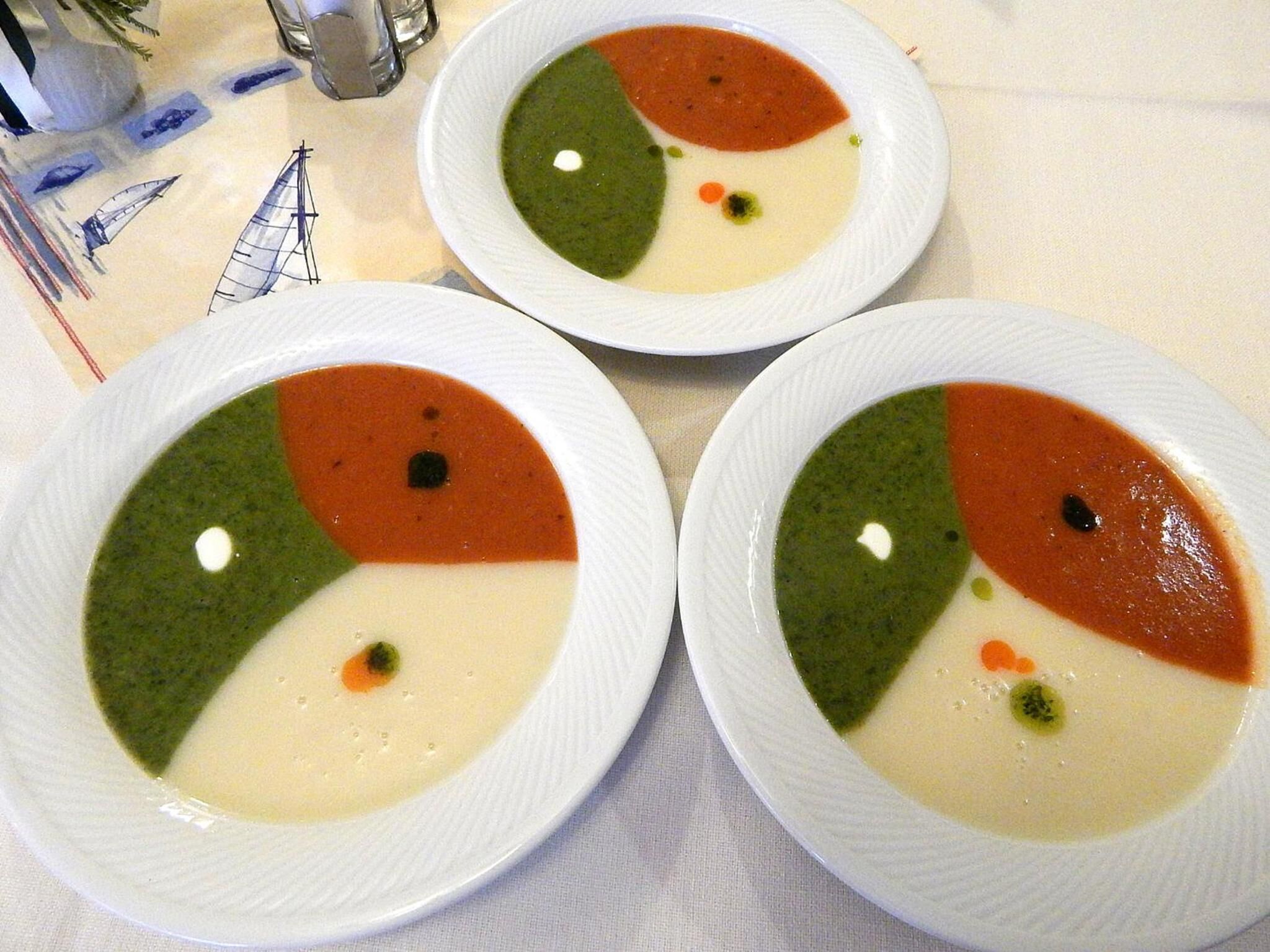Drie kommen soep met verschillende kleuren, op een tafel gezet.