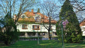 A traditional house with a red-tiled roof, surrounded by well-maintained gardens and trees.