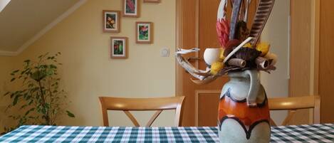 Une table à manger recouverte d’une nappe à carreaux, un vase agrémenté d’une composition florale et une chaise en bois.