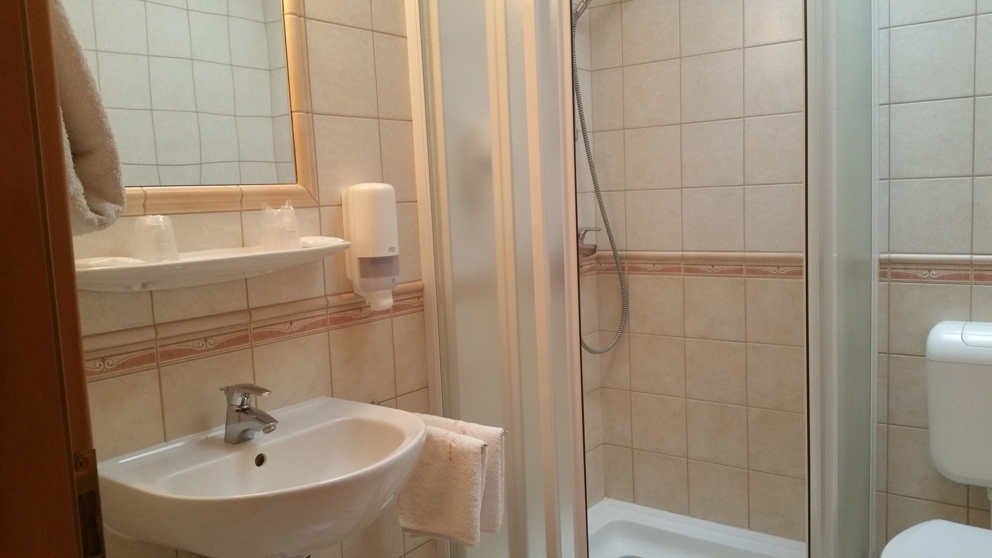 A bathroom with a sink, mirror, towel rack, and shower area.