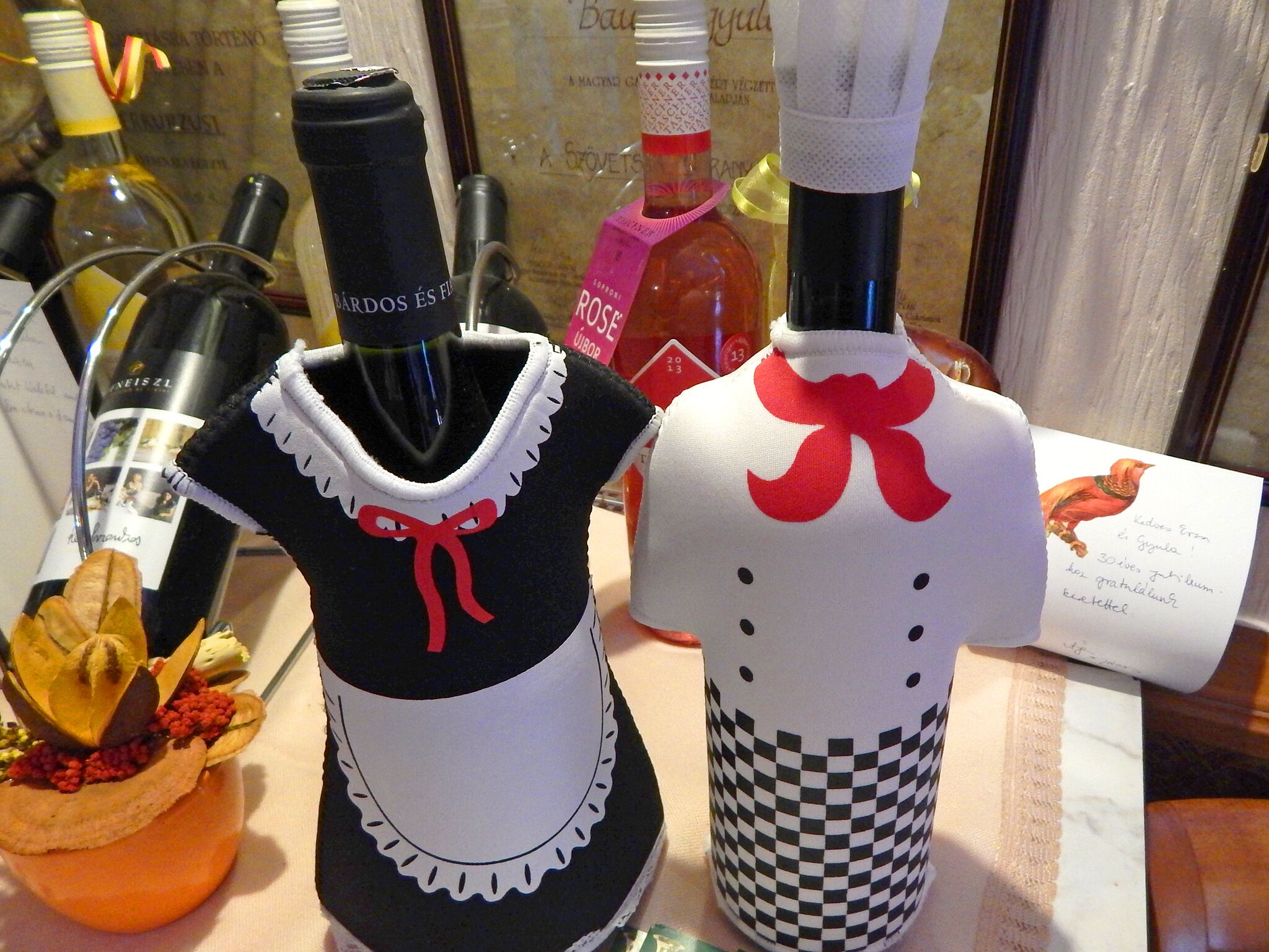 Una exhibición de botellas de vino y un adorno que parece un vestido con un lazo rojo.