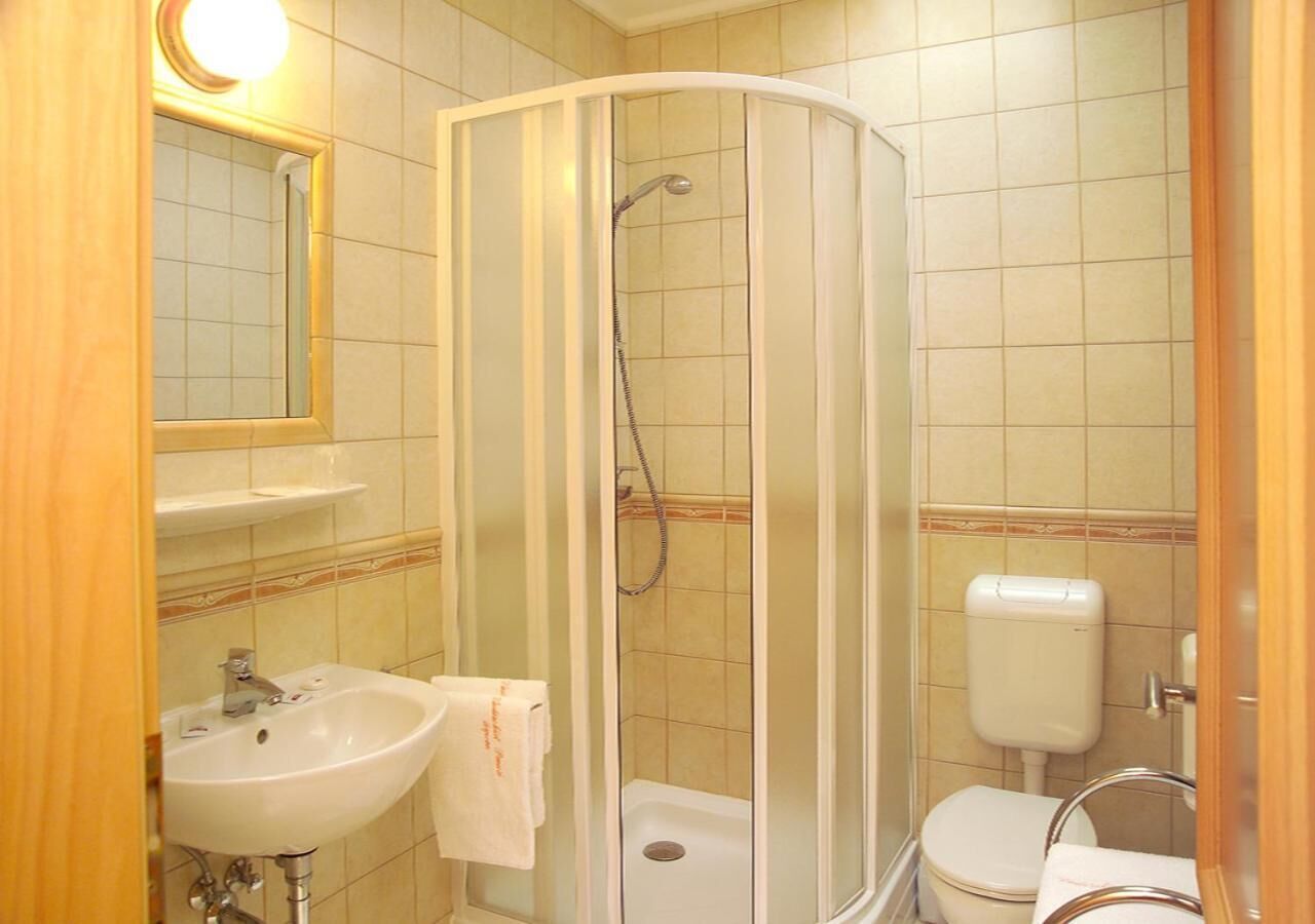 Kylpyhuone, jossa on lasiseinällä varustettu suihku, pesuallas, wc ja peili.