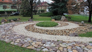 A garden with a circular stone pathway, surrounded by gravel and grass.