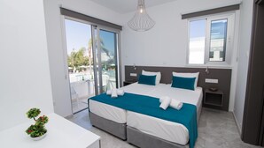 A modern hotel room with a large bed, a balcony with a view, and a small table with a plant. - Lantiana Gardens (Paralimni)