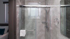 A modern bathroom with a glass-enclosed shower, a towel rack, and a large mirror. - Lantiana Gardens (Paralimni)