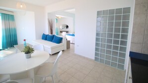 A modern living room with a white sofa, blue cushions, a dining table with chairs, and a potted plant. - Lantiana Gardens (Paralimni)