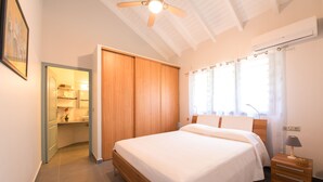Une chambre à coucher avec un lit en bois, une table de chevet, un ventilateur de plafond et une armoire.
