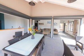 Een ruime woonkamer met een eettafel, banken en een keukenhoek.