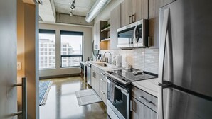 Una cocina moderna con electrodomésticos de acero inoxidable, armarios de madera y un amplio ventanal con vistas a la ciudad.