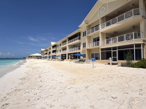 A beachfront hotel with multiple balconies, sun loungers, and umbrellas. - Laguna Del Mar #08 (Seven Mile Beach)