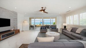 A modern living room with a flat-screen TV, grey sofas, a coffee table, and a ceiling fan. - Laguna Del Mar #08 (Seven Mile Beach)