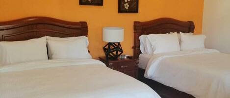 Habitación de hotel con dos camas, aire acondicionado y dos cuadros de flores colgados en la pared.