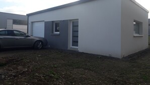 En moderne bygning i et plan med fladt tag, garageport og et lille vindue.