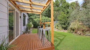 A wooden deck with a pergola, a small garden, and a house with a window and a door. - Cobden & Wills - In the heart of Bright (Bright)