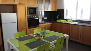 Eine kleine Küche mit Holzausstattung, einem weißen Kühlschrank, einer Mikrowelle und einem Spülbecken.