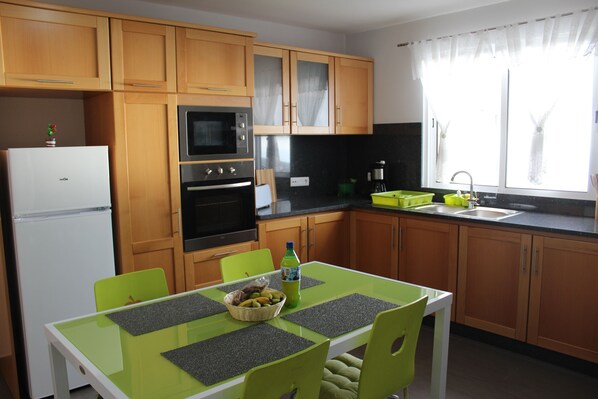 A compact kitchen with wooden cabinets, a white refrigerator, a microwave, and a sink.