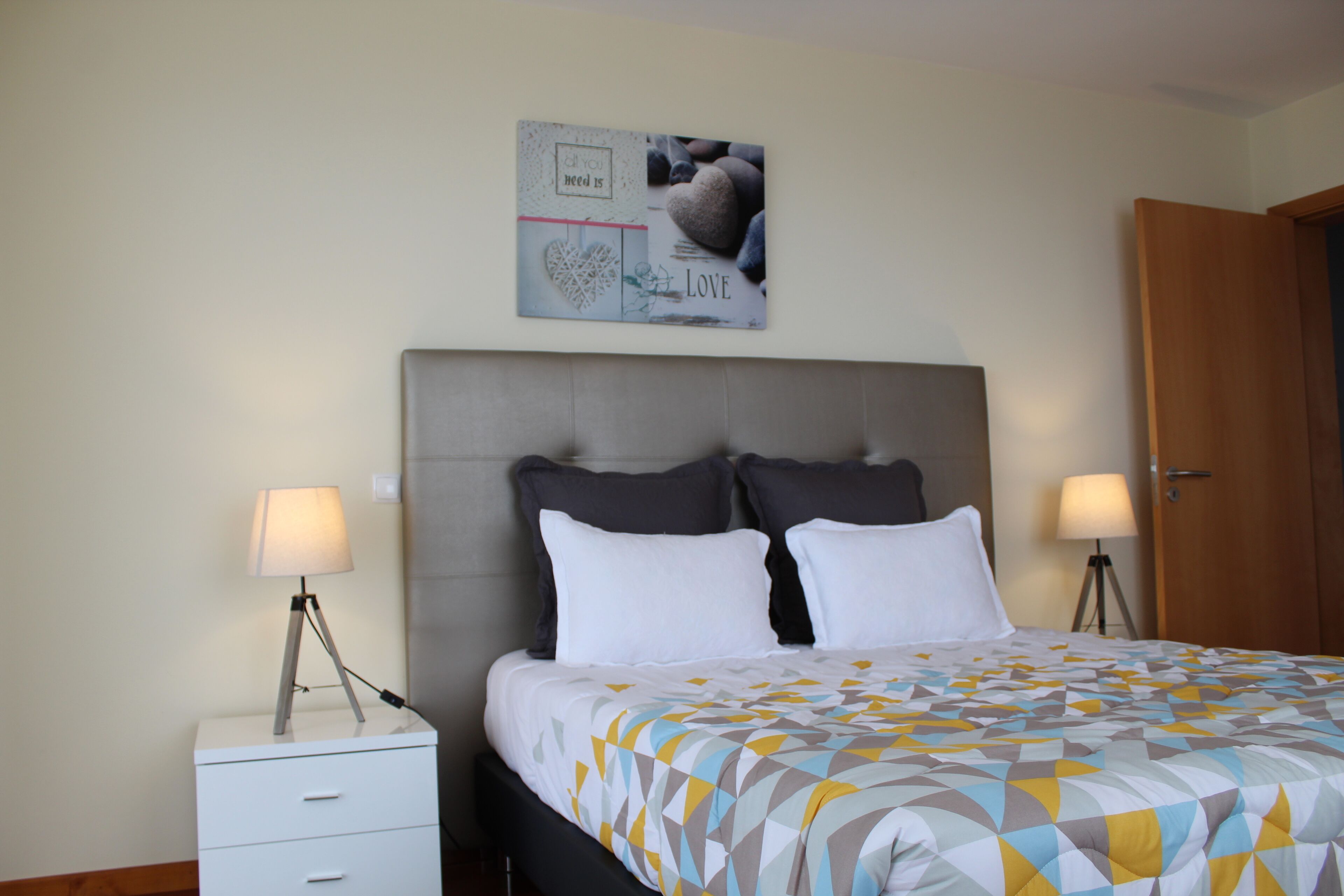 Una camera da letto con un letto, due comodini, un'opera d'arte appesa al muro e una porta.
