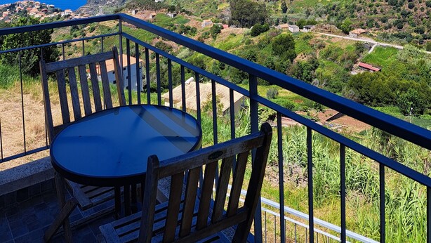 Ein Balkon mit Tisch und Stühlen mit Blick auf eine Küstenlandschaft.