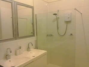 Huis | Badkamer | Een bad/douchecombinatie, een diep bad, een haardroger, handdoeken