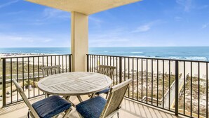 A balcony with a round table and chairs, overlooking a beach with a clear view of the ocean and a sandy shore. - Beachfront 1BR @ Phoenix IV • Sleeps 4 • Stunning Views, Balcony & Resort Amenities (Orange Beach)
