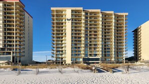 A high-rise hotel with multiple balconies, a central atrium, and a beachside location. - Beachfront 1BR @ Phoenix IV • Sleeps 4 • Stunning Views, Balcony & Resort Amenities (Orange Beach)