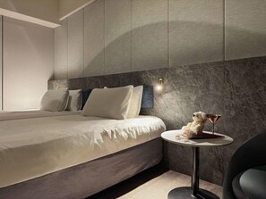 A modern bedroom with a bed, pillows, a nightstand, a lamp, and a teddy bear. - Metro Hotel (Yunlin)