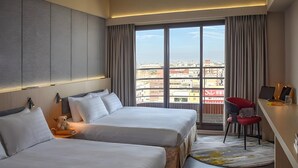 A hotel room with two beds, a desk, a chair, and a large window with a city view. - Metro Hotel (Yunlin)