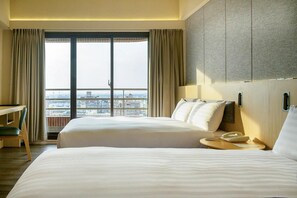 A hotel room with two beds, a desk, and a view of the city. - Metro Hotel (Yunlin)