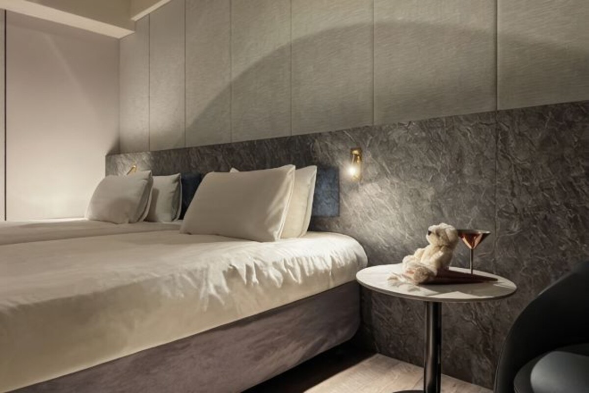 A modern bedroom with a bed, a round table, and a small decorative item.