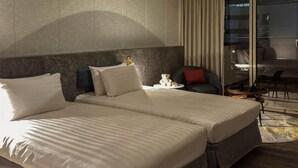 A hotel room with two beds, a desk, a chair, and a large window with curtains. - Metro Hotel (Yunlin)