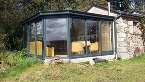 A conservatory with large glass doors, a stone wall, and a small window. - Room, Jacuzzi, Table d'hôtes on reservation (TREDUDER)