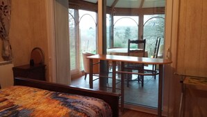 A bedroom with a bed, a desk, and a view of a patio with a table and chairs. - Room, Jacuzzi, Table d'hôtes on reservation (TREDUDER)
