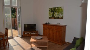 Una sala de estar con un mueble de madera, un televisor, una mesa de comedor y un sofá.