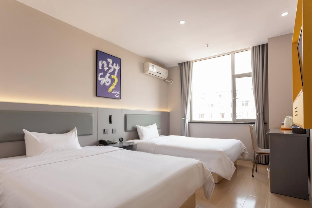 Ett hotellrum med två sängar, ett skrivbord och ett stort fönster.