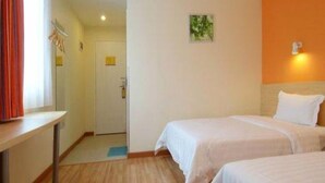 A hotel room with two beds, a small desk, a door, and a wall-mounted light fixture. - 7days Inn Hotel (Xinzhou)