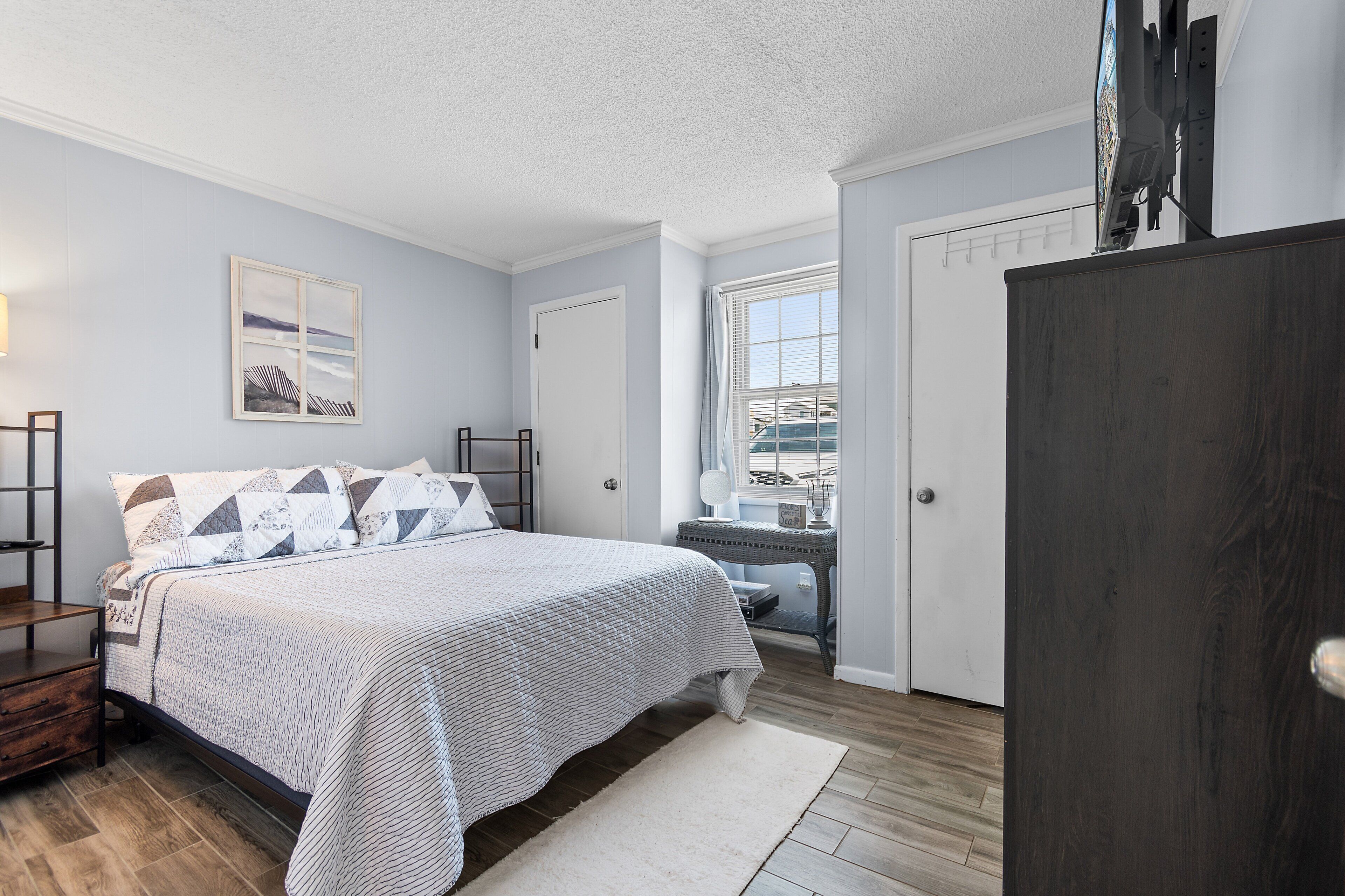 A bedroom with a bed, bedside tables, a window, and a door.