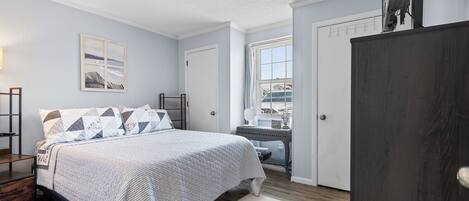 A bedroom with a bed, bedside tables, a window, and a door.