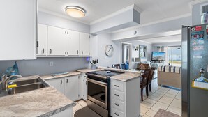 A kitchen with white cabinets, a built-in oven, a sink, and a refrigerator. - "Shore Beats Work" - 2nd Row Condo w/ Community Pool, 4 Bedrooms / 2 Bathrooms (Holden Beach)