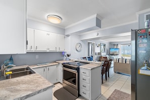 A kitchen with white cabinets, a built-in oven, a sink, and a refrigerator.
